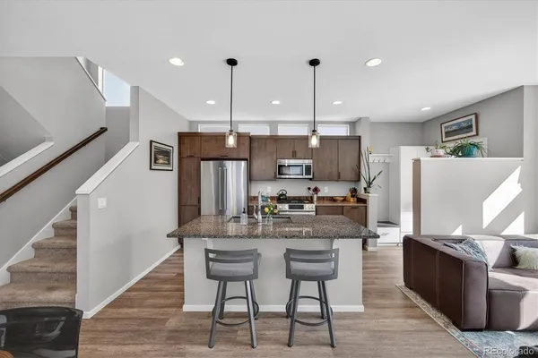 a kitchen with stainless steel appliances kitchen island granite countertop a table chairs and a refrigerator