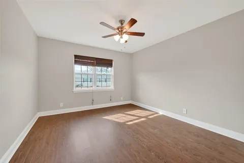 an empty room with wooden floor ceiling fan and windows