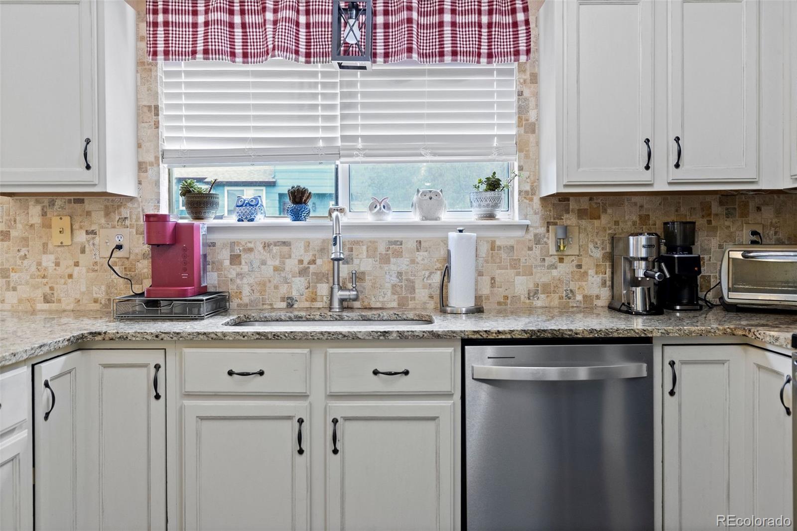 10565 Hyacinth Place Highlands Ranch, CO 80129 - Photo 12 of 33 a kitchen with granite countertop white cabinets and a sink