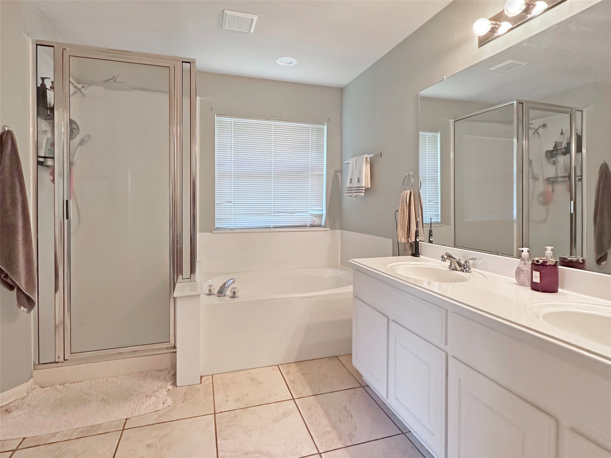 20213 Kearney Hill Road Pflugerville, TX 78660 - Photo 16 of 27 A well-appointed bathroom with a dual vanity and separate soaking tub and glass-enclosed shower.