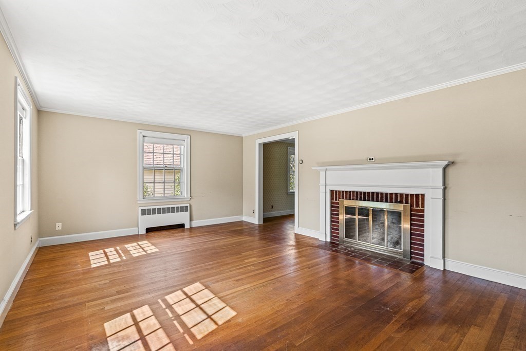 7 Spring Street Lexington, MA 02421 - Photo 4 of 25 an empty room with wooden floor fireplace and windows