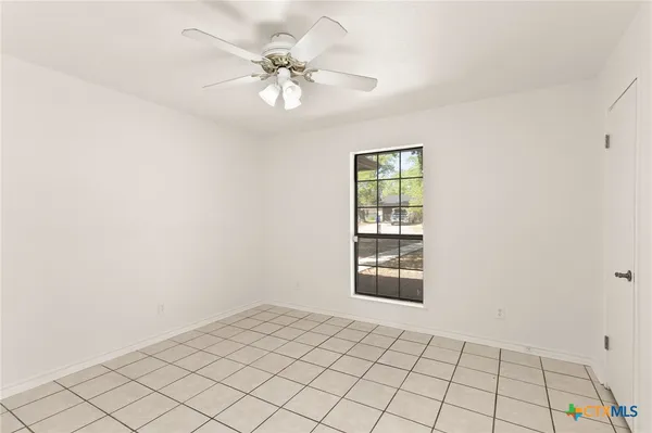 an empty room with windows and fan