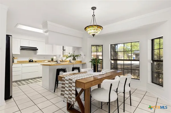 a kitchen with a dining table chairs sink and cabinets