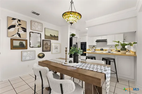 a dining room with stainless steel appliances furniture a chandelier and kitchen view