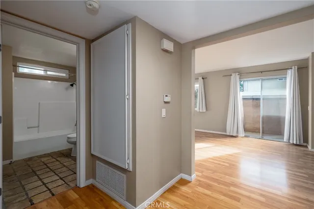 a view of a hallway with wooden floor and a bathroom