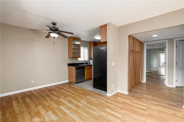 a view of kitchen and empty room with wooden floor