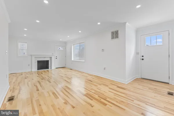 a view of an empty room with wooden floor and a fireplace