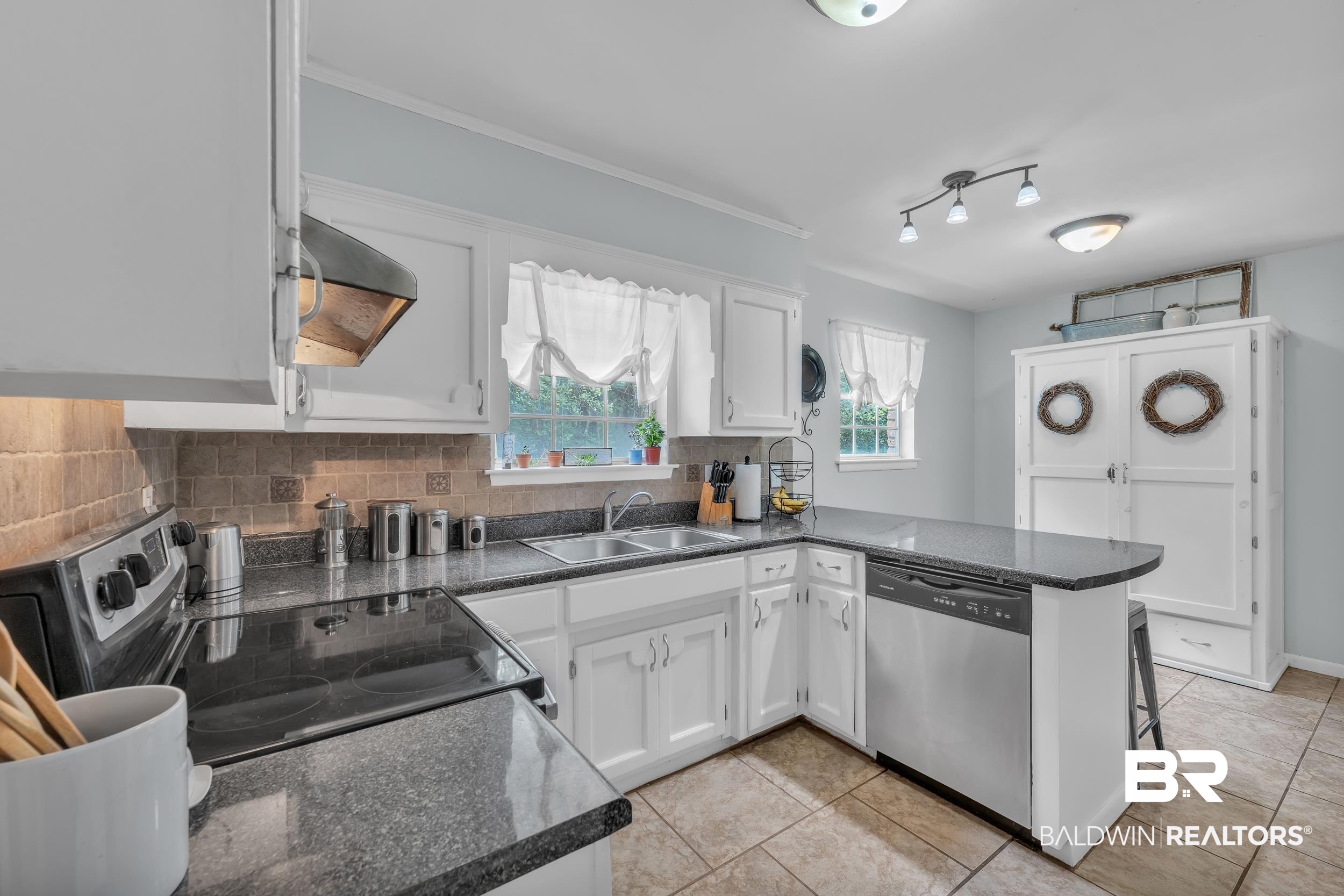 224 Cache Circle Mobile, AL 36611 - Photo 13 of 42 Kitchen with appliances with stainless steel finishes, a sink, white cabinets, decorative backsplash, and light tile patterned flooring