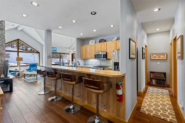 a kitchen with stainless steel appliances granite countertop a table chairs refrigerator and sink