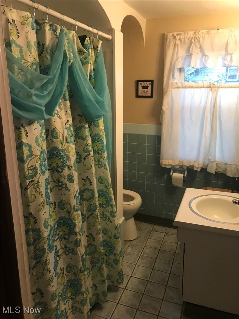 720 Kipling Street Akron, OH 44306 - Photo 16 of 21 Full bath featuring tile walls, tile patterned floors, a wainscoted wall, vanity, and toilet
