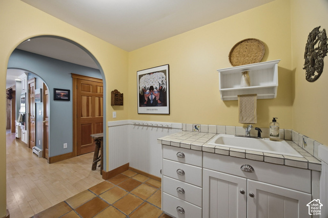 725 Canyon Road Smithfield, UT 84335 - Photo 34 of 100 Built-in sink with tiled countertop, wood-finish flooring, recessed wall paneling, and arched doorways