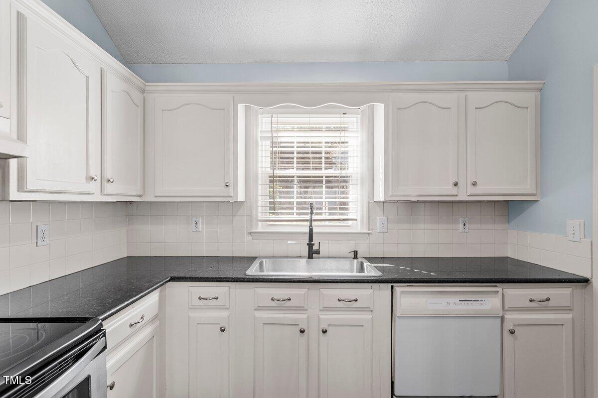 8337 Greywinds Drive Raleigh, NC 27615 - Photo 13 of 27 a kitchen with granite countertop white cabinets and a window