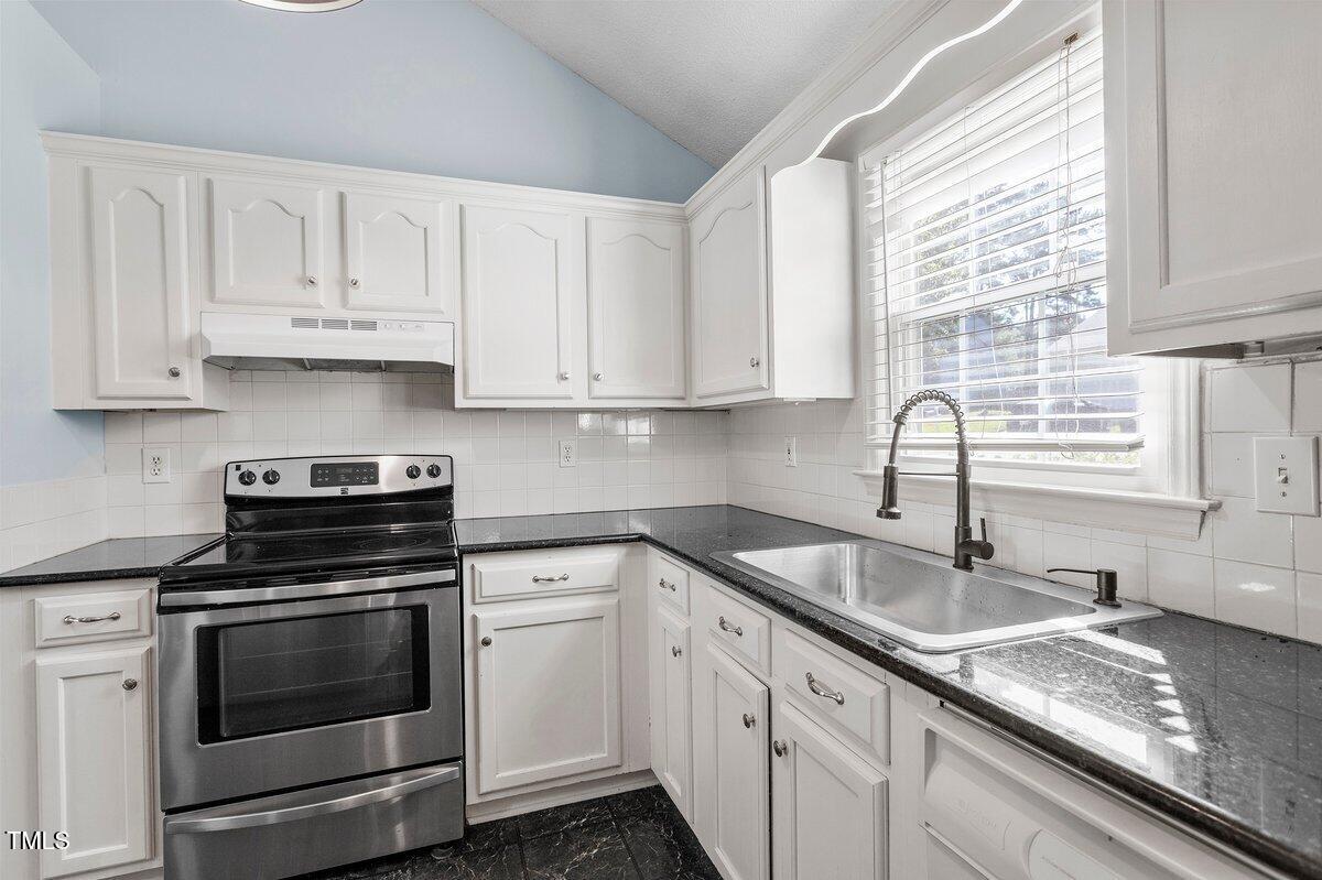 8337 Greywinds Drive Raleigh, NC 27615 - Photo 17 of 27 a kitchen with granite countertop white cabinets and a stove