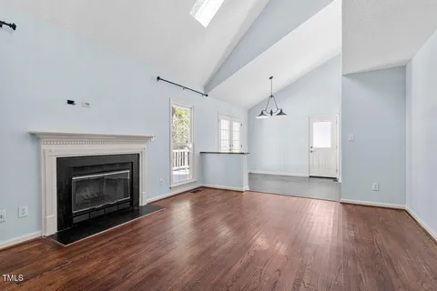 a view of an empty room with wooden floor fireplace and a window