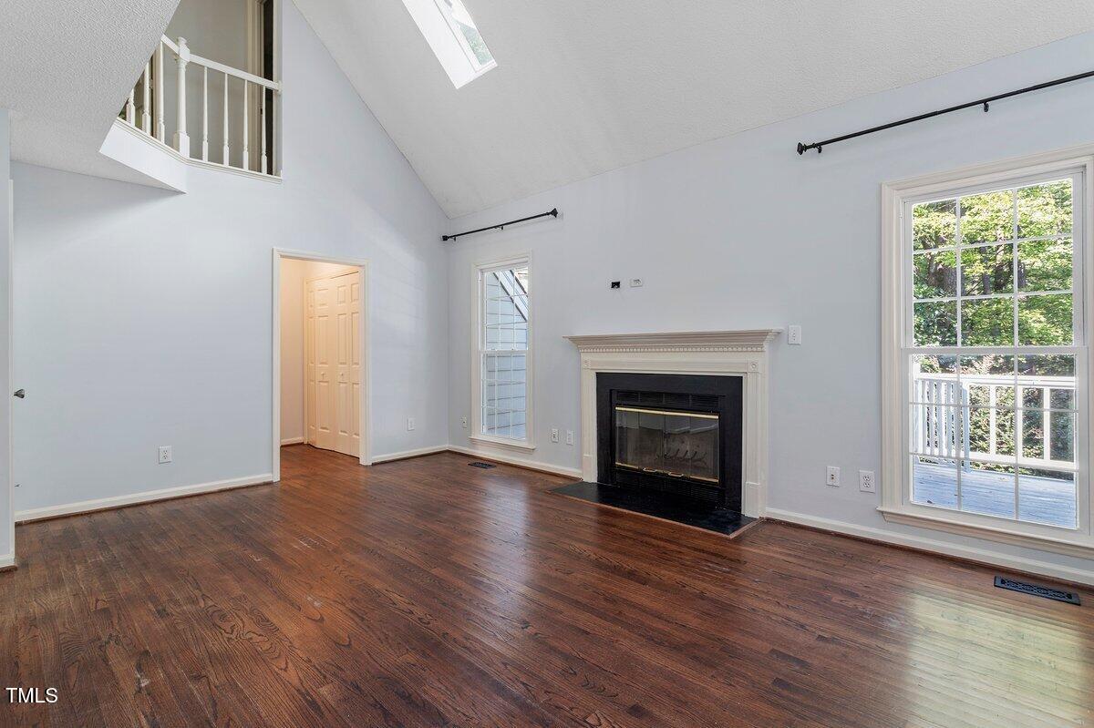 8337 Greywinds Drive Raleigh, NC 27615 - Photo 10 of 27 an empty room with wooden floor fireplace and windows