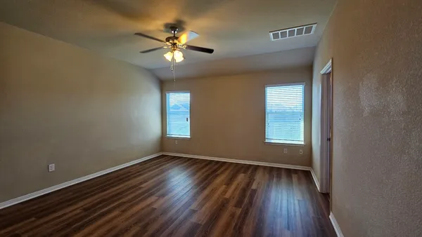 a view of wooden floor and a chandelier fan in a room
