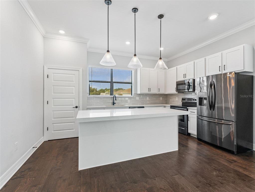 3421 West Horatio Street, Unit 109 Tampa, FL 33609 - Photo 6 of 20 a large kitchen with kitchen island a stove a sink a center island a refrigerator and a wooden floor