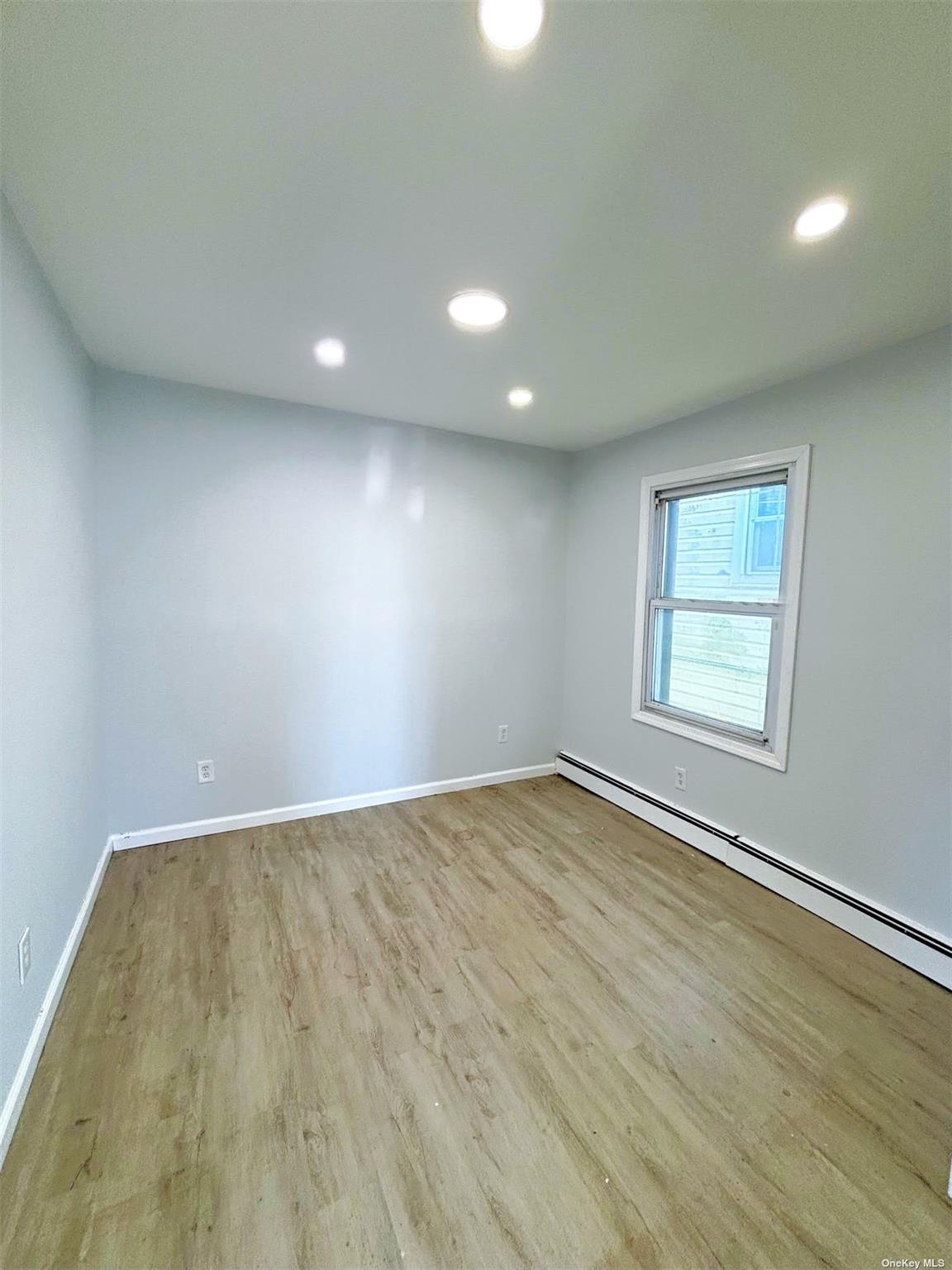 36 Walnut Road Inwood, NY 11096 - Photo 6 of 9 an empty room with wooden floor and windows