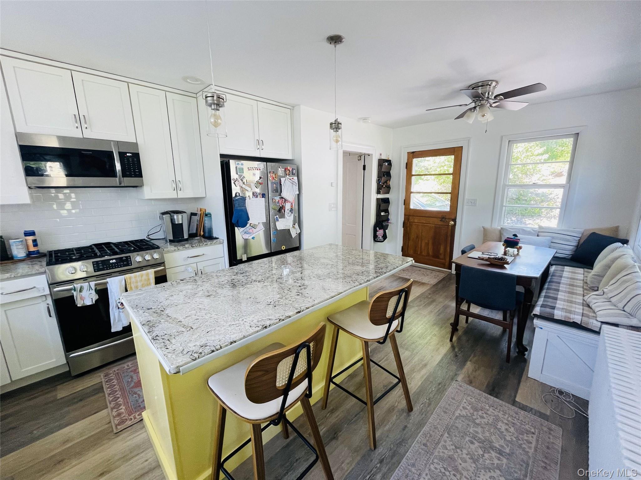 12 Parrott Street Cold Spring, NY 10516 - Photo 2 of 18 Kitchen with new stainless steel appliances, tasteful backsplash, a kitchen breakfast bar and wood floors