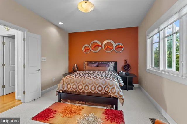 a spacious bedroom with a bed a dresser and a large window