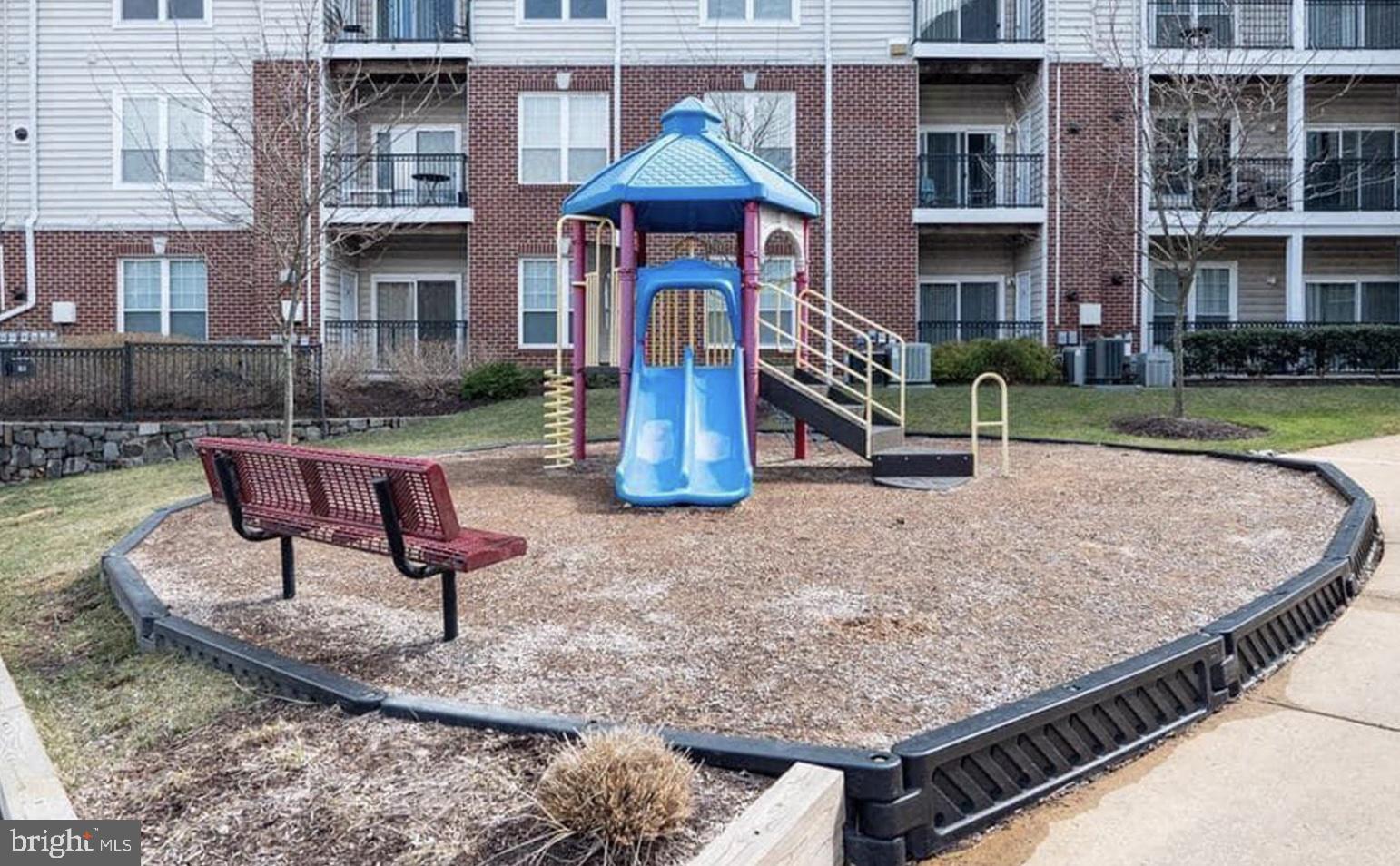 1601 Spring Gate Dr., Unit 1411 McLean, VA 22102 - Photo 37 of 39 a park with tall buildings and a bench next to a road