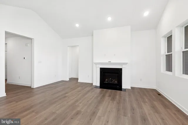an empty room with wooden floor and a fireplace