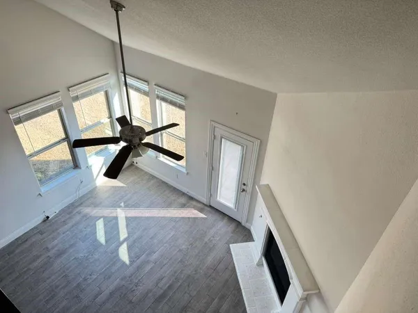 an empty room with wooden floor chandelier and windows