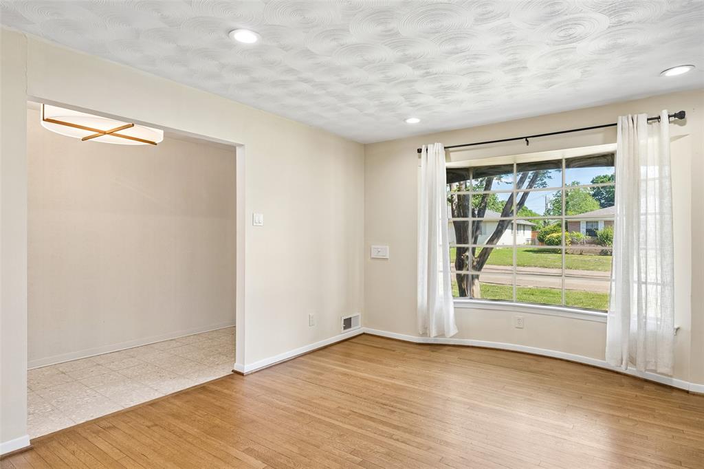 8049 Woodhue Road Dallas, TX 75228 - Photo 11 of 24 a view of an empty room with wooden floor and a window