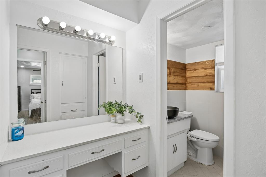 8049 Woodhue Road Dallas, TX 75228 - Photo 19 of 24 a spacious bathroom with a granite countertop sink a toilet and a mirror