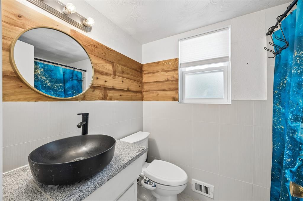 8049 Woodhue Road Dallas, TX 75228 - Photo 20 of 24 a bathroom with a toilet and a mirror