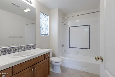 a bathroom with a toilet a sink a mirror and a window