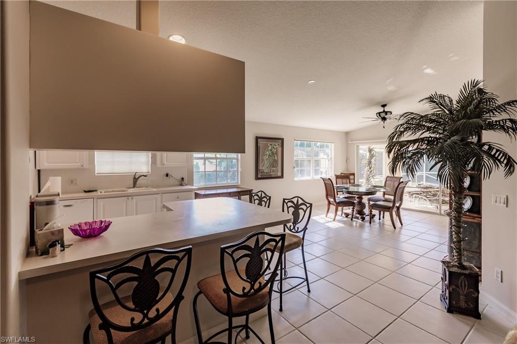 4113 Tabago Lane Naples, FL 34119 - Photo 12 of 50 Kitchen with ceiling fan, light tile patterned floors, a breakfast bar area, white cabinetry, and lofted ceiling