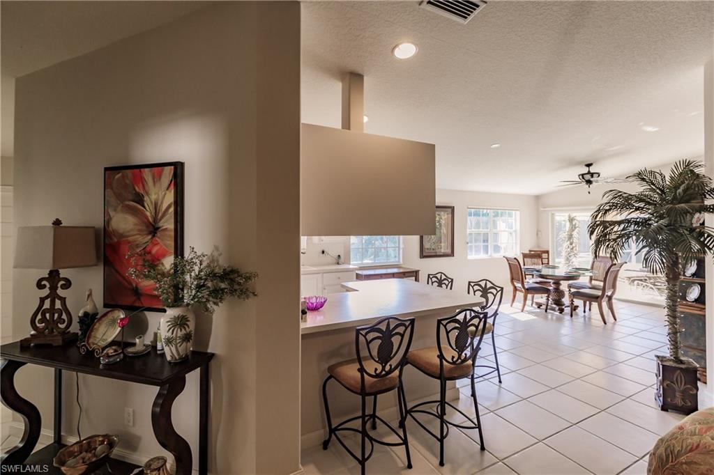 4113 Tabago Lane Naples, FL 34119 - Photo 13 of 50 Kitchen with vaulted ceiling, ceiling fan, light tile patterned floors, kitchen peninsula, and a breakfast bar area