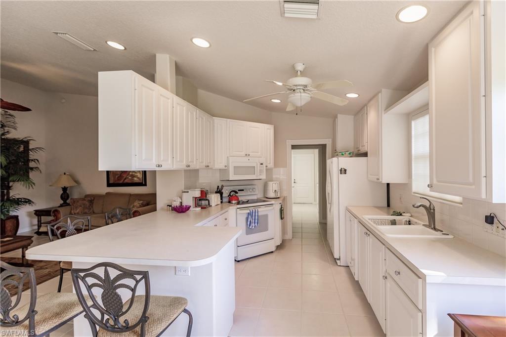 4113 Tabago Lane Naples, FL 34119 - Photo 14 of 50 Kitchen with kitchen peninsula, white appliances, sink, white cabinets, and light tile patterned flooring