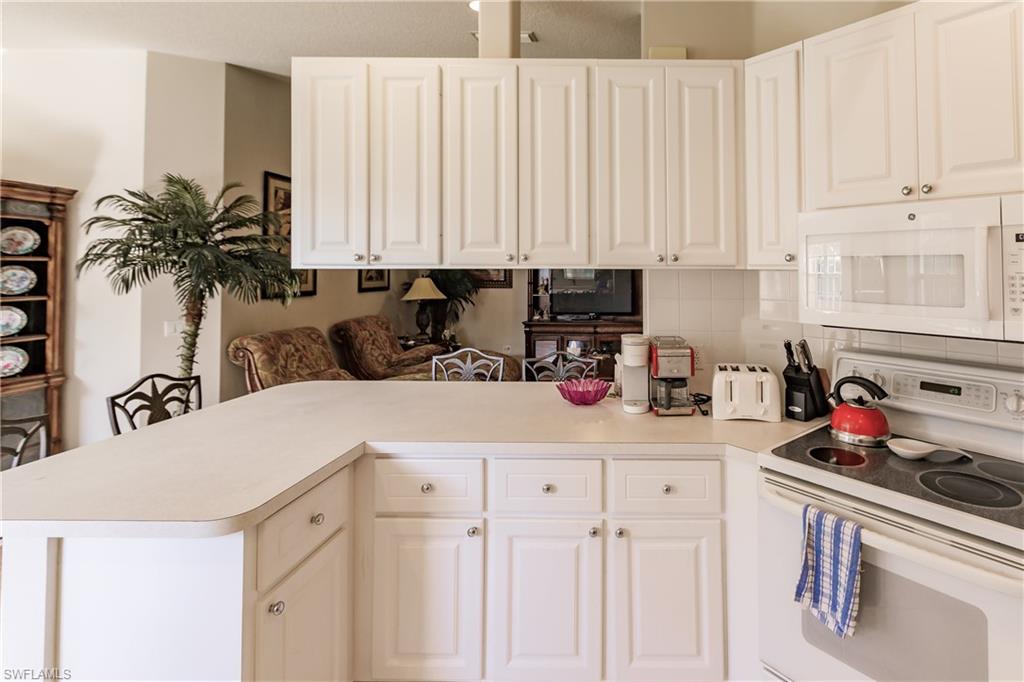 4113 Tabago Lane Naples, FL 34119 - Photo 16 of 50 Kitchen with kitchen peninsula, white appliances, white cabinetry, and backsplash