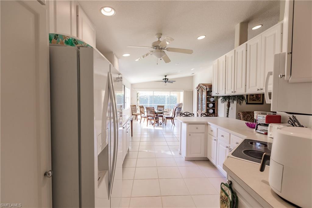 4113 Tabago Lane Naples, FL 34119 - Photo 17 of 50 Kitchen featuring lofted ceiling, white cabinets, white fridge with ice dispenser, light tile patterned flooring, and kitchen peninsula