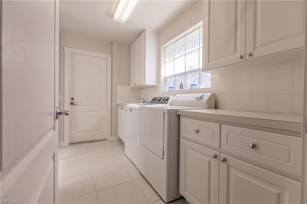4113 Tabago Lane Naples, FL 34119 - Photo 34 of 50 Laundry area with washer and dryer, light tile patterned floors, and cabinets