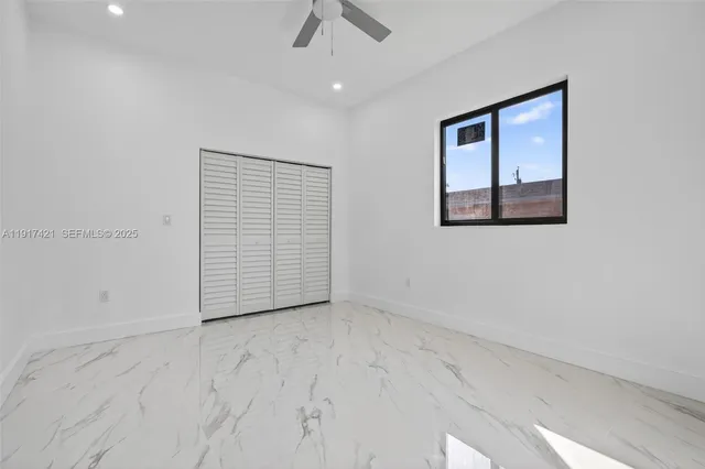 an empty room with ceiling fan and windows