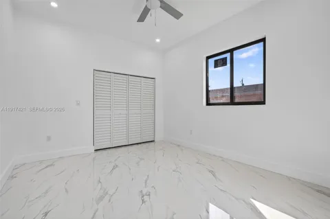 an empty room with ceiling fan and windows