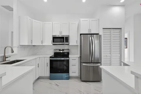 a kitchen with a refrigerator stove and white cabinets