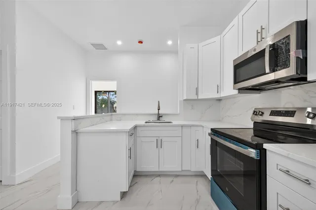 a kitchen with stainless steel appliances a stove microwave and sink