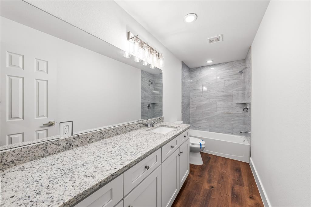 1128 Newton Road Ferris, TX 75125 - Photo 20 of 28 Bathroom featuring a double vanity with granite countertops, undermount sinks, and white shaker cabinetry