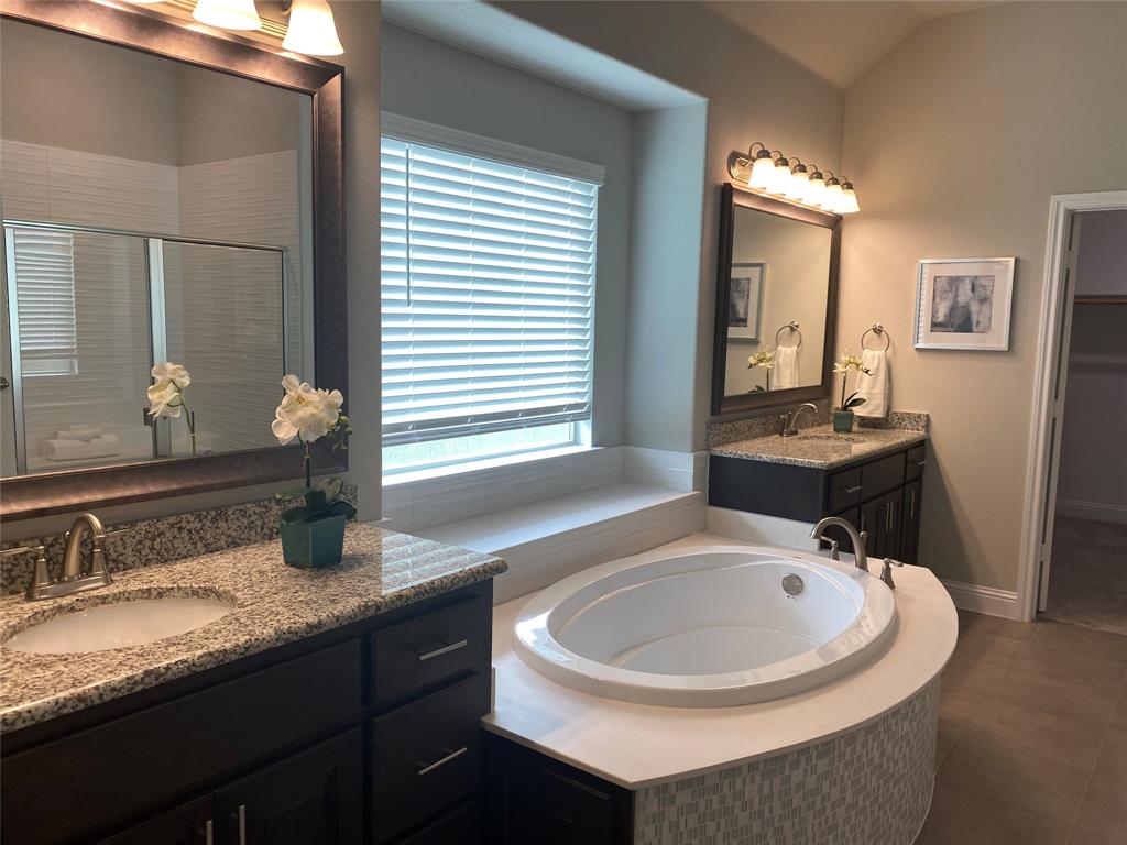 209 Johnson Street Granbury, TX 76048 - Photo 28 of 40 Bathroom with a wealth of natural light, a relaxing tiled bath, vanity with extensive cabinet space, and tile flooring