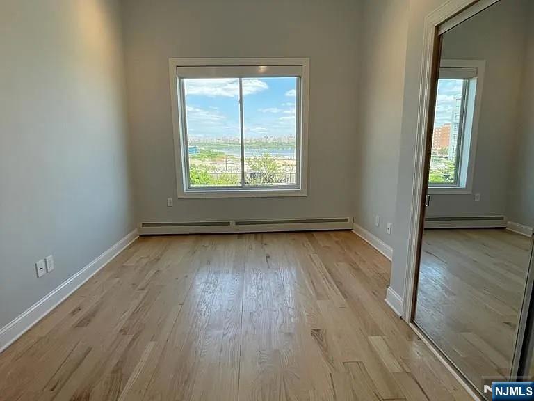 9009 Riverside Place, Unit 2 North Bergen, NJ 07047 - Photo 5 of 14 an empty room with wooden floor and windows
