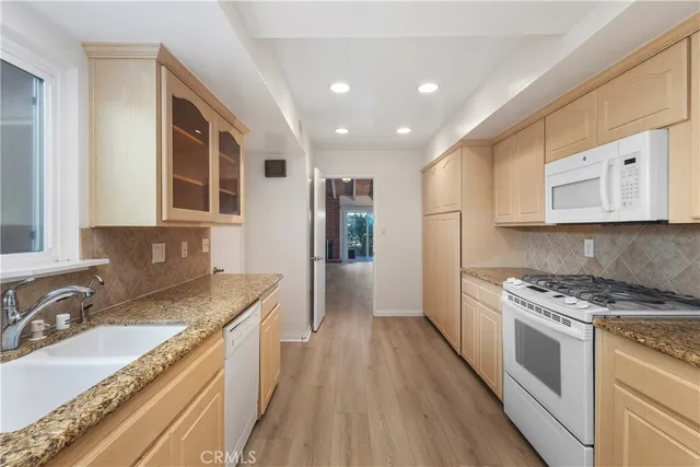 a kitchen with granite countertop stainless steel appliances a sink stove top oven and cabinets