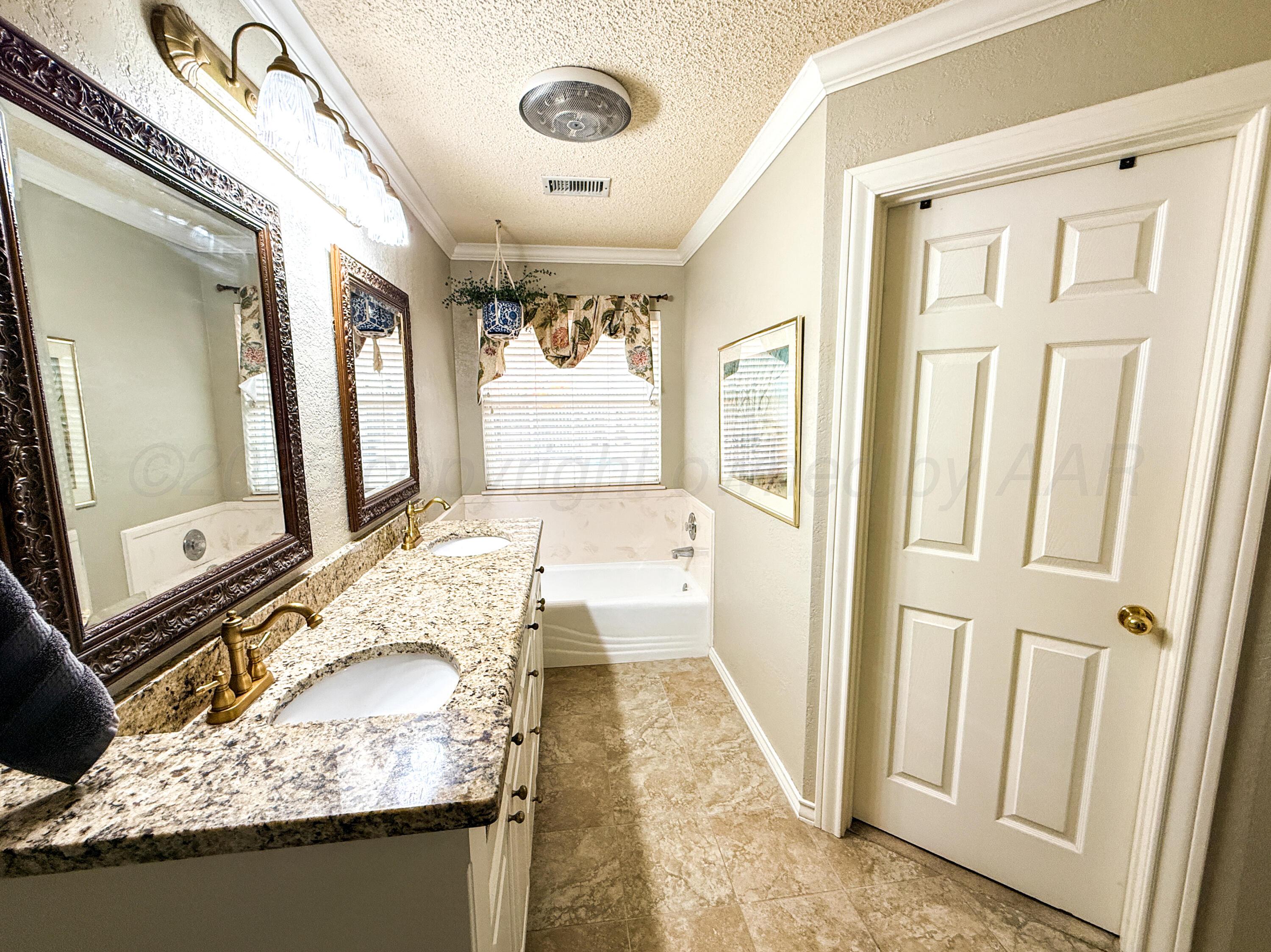 5724 Spencer Street Amarillo, TX 79109 - Photo 26 of 37 a bathroom with a granite countertop sink a mirror and a bathtub