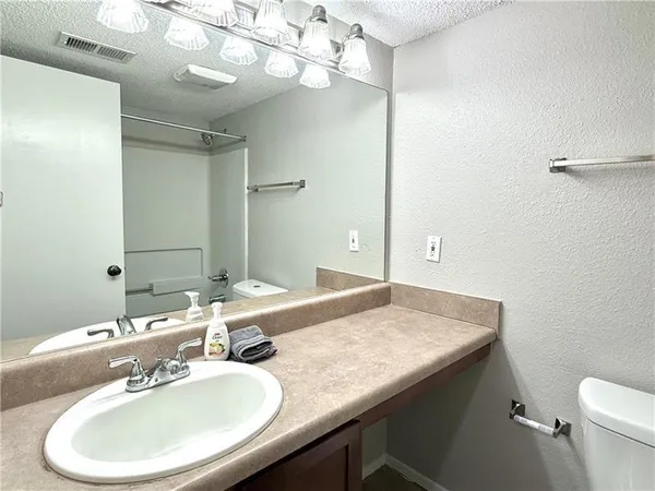 a bathroom with a granite countertop sink a toilet and a mirror