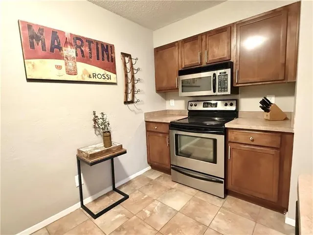 a kitchen with stainless steel appliances kitchen island granite countertop a stove a sink and a refrigerator