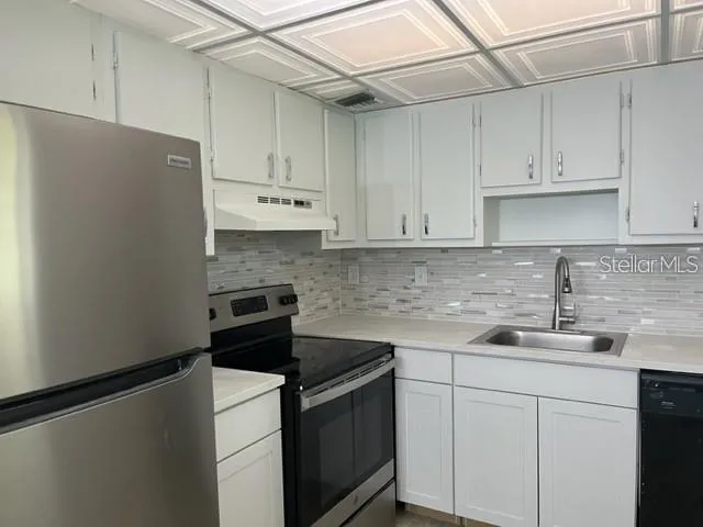 a kitchen with stainless steel appliances white cabinets and a refrigerator
