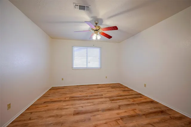 an empty room with a window and a fan